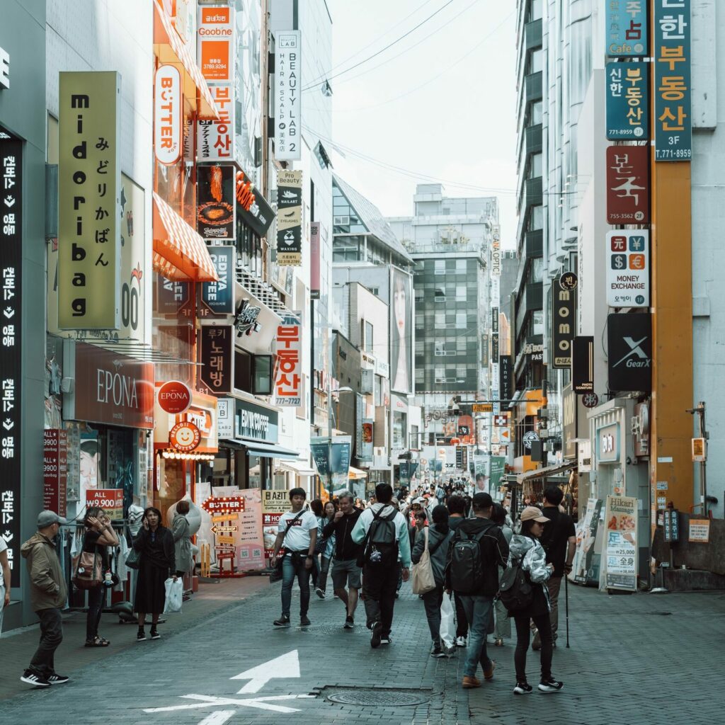 Lively street view with people and neon signs in Seoul, South Korea, showcasing urban life.